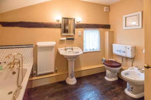 萨德伯里Cliftons Cottage, Clare的浴室配有盥洗盆、卫生间和浴缸。
