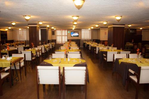基多12月6日酒店的一间配有桌子和白色椅子的用餐室