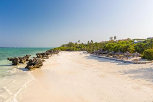 马特姆维Sunshine Bay Hotel Zanzibar的一片拥有一排小屋和海洋的海滩