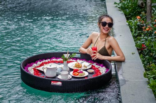 乌布Tri Dewi Residence by Pramana Villas的坐在圆桌旁,在水里吃食物的女人