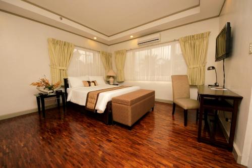 马尼拉卡萨普拉套房酒店的一间卧室配有一张床、一张桌子和一把椅子