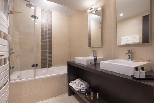 贝勒普拉涅Hôtel Club MMV Les 2 Domaines的浴室配有水槽、淋浴和浴缸。
