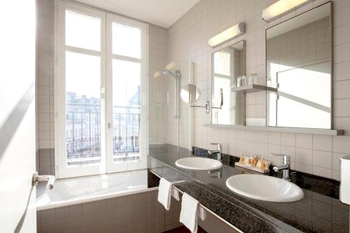 波尔多Hôtel de Normandie的一间带两个盥洗盆和大镜子的浴室