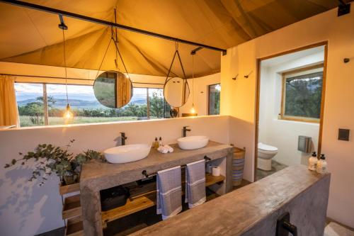 伯格维尔Sasi Africa Luxury Tented Bush Lodge的一间带两个盥洗盆和大镜子的浴室