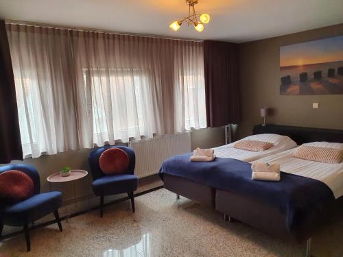 尼乌弗利特Hotel Maurice的酒店客房,配有两张床和两把椅子