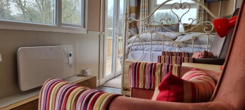 奥斯威斯Riverside Cabin in Shropshire的一间带椅子和一张带窗户的床的房间