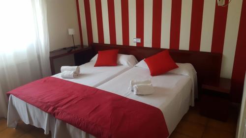 索里亚圣安德烈斯旅馆的一间卧室配有一张带红色和白色枕头的大床