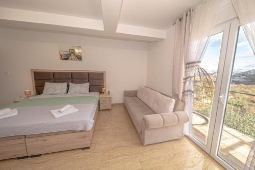 威尔帕扎Skadar lake Apartments Pajovic的一间卧室配有一张床、一张沙发和一个窗口