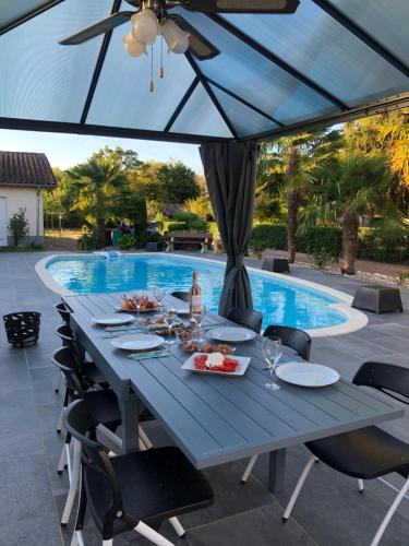 贝尔热拉克Villa Bergerac avec Piscine的一张蓝色桌子,上面有食物,旁边是游泳池