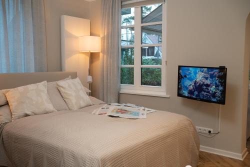 蒂门多弗施特兰德Studio-Apartment Piccolino 26的卧室配有一张床铺,墙上配有电视