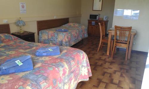 Goolgowi古尔高伊公路汽车旅馆的酒店客房带两张床和一张桌子以及椅子。