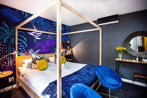 弗朗斯胡克Franschhoek Maison du Cap的一间卧室配有天蓬床和蓝色椅子