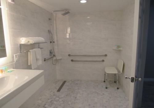 安纳海姆Capri Suites Anaheim的带淋浴和盥洗盆的白色浴室