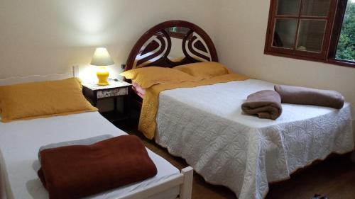 Caparaó VelhoHostel Café的一间卧室配有两张床和一张带台灯的桌子
