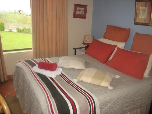 爱德华港Bottlenose B&B的一间卧室配有一张带红色枕头的床和一扇窗户
