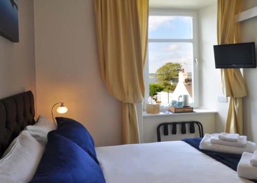 BowmoreAn Cuan Bed & Breakfast的一间卧室配有一张带蓝色枕头的床和一扇窗户。
