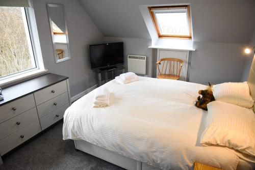 乌伊格5 Glenconon Bed and Breakfast的卧室配有一张白色的床,上面有一只动物填充物