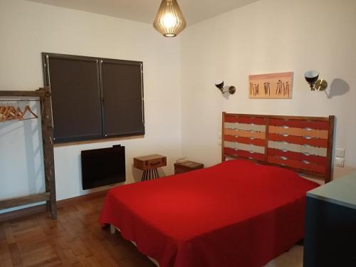 GueuresLA MENUISERIE D'ANDRE的一间卧室配有红色的床和电视