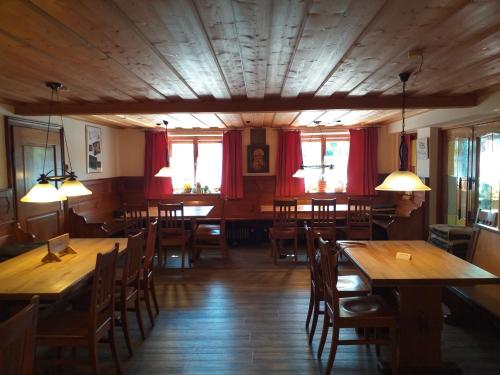 Neukirchen am TeisenbergMesnerwirt的餐厅设有木桌和椅子以及红色窗帘