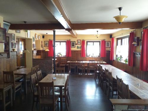 Neukirchen am TeisenbergMesnerwirt的餐厅设有木桌和椅子以及红色窗帘
