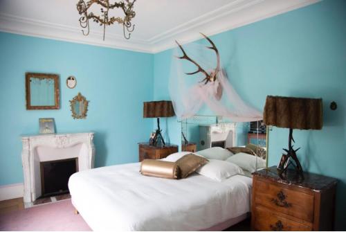 普罗万家园酒店的一间蓝色卧室,配有两张床和一个壁炉