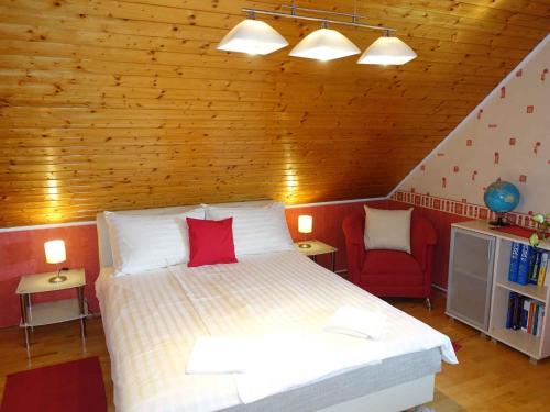根尼斯迪亚斯Holiday home in Gyenesdias - Balaton 40755的一间卧室配有一张大床和一张红色椅子