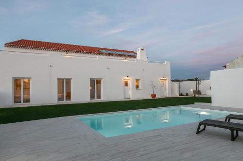 CarvalhalPé no Campo Suites and Villa的一座白色的房子,前面设有一个游泳池