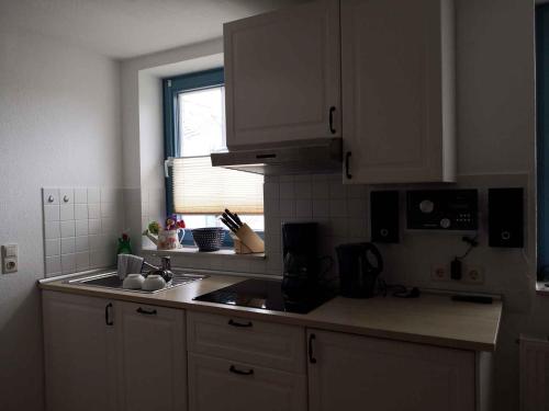 SandortApartment in Sellin/Insel Rügen 37917的厨房配有白色橱柜、水槽和窗户。