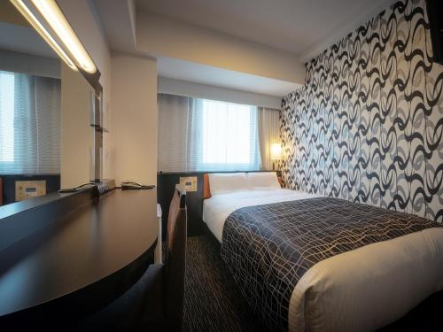 古河市APA Hotel Ibaraki Koga Ekimae的配有一张床和一张书桌的酒店客房
