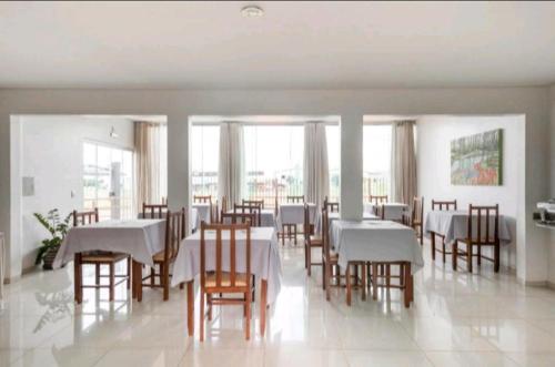 大坎普Nosso Hotel的用餐室配有白色的桌子和木椅