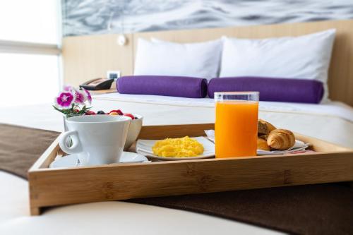 利马帕尔梅托圣博尔哈商务酒店的床上的食品和橙汁托盘