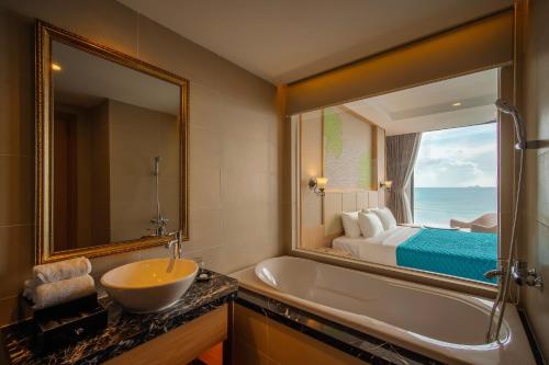 芽庄Navada Beach Hotel的带浴缸、水槽和镜子的浴室