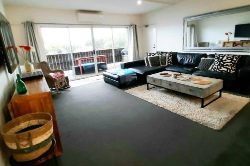 Cape WoolamaiModern 3 bedroom apartment, beach, surf & shops的客厅配有黑色沙发和桌子