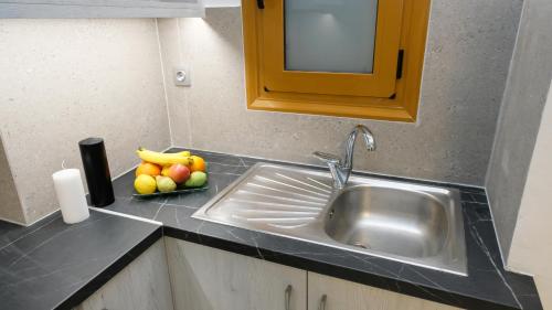 罗希姆诺Constantine Fortezza Rooms的厨房柜台设有水槽和一碗水果