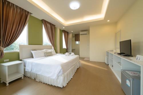 清莱班罗诺酒店的卧室配有白色的床和电视。