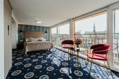 克拉科夫简恩酒店的一间带一张床和两把椅子的卧室,位于阳台