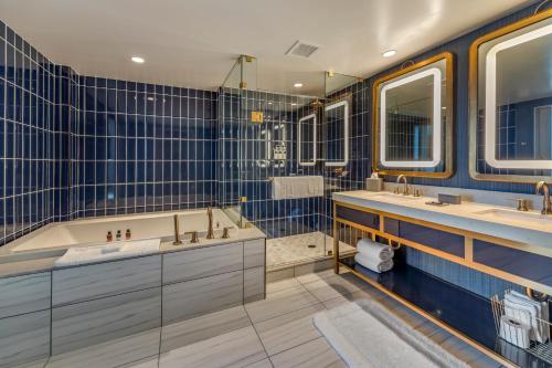 俄克拉何马城Omni Oklahoma City Hotel的蓝色瓷砖浴室设有2个水槽和1个浴缸