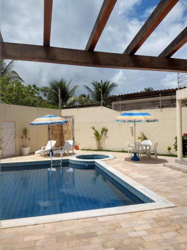 拉巴拉德纳圣米格尔Casa na Barra de São Miguel的一个带两把蓝色遮阳伞和椅子的游泳池