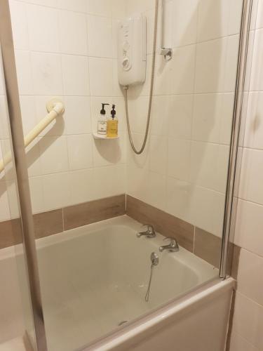 恩尼斯基林柳岸楼酒店的墙上配有电话和浴缸的淋浴