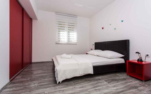 瓦比尼科Apartment in Vrbnik/Insel Krk 36800的一间卧室配有一张床和一张红色的桌子