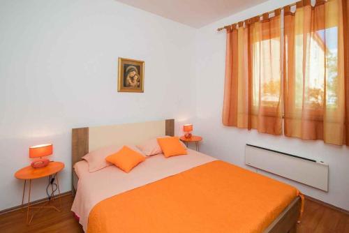 瓦比尼科Apartment in Vrbnik/Insel Krk 36842的一间卧室配有一张带橙色床单和两盏灯的床。
