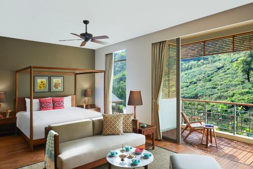 KurseongTaj Chia Kutir Resort & Spa Darjeeling的一间卧室配有一张床、一张沙发和一个大窗户