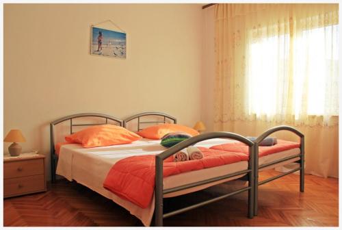 斯拉汀Apartment in Slatine with sea view, balcony, air conditioning, Wi-Fi (4782-1)的一间卧室配有带橙色枕头的床和窗户。