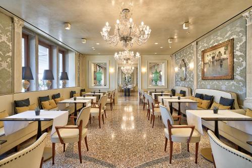威尼斯Londra Palace Venezia的一间带桌椅和吊灯的餐厅