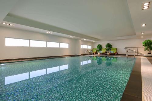 马斯喀特Wyndham Garden Muscat Al Khuwair的一座带游泳池的大楼内的大型游泳池
