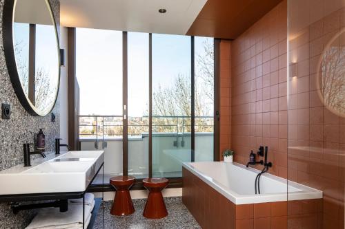 马恩河畔诺让Hôtel du Port的一间带两个盥洗盆和浴缸的浴室以及大窗户。