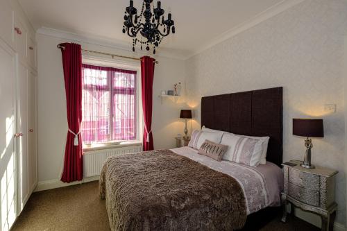斯沃尼奇罗伯茨布鲁克旅馆的一间卧室配有一张带红色窗帘和吊灯的床。