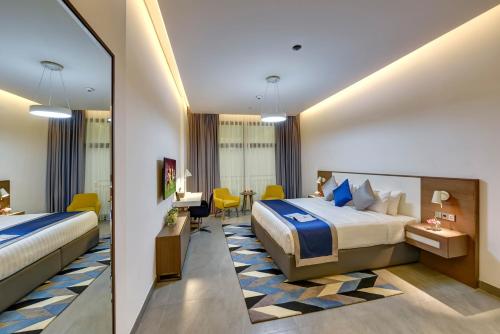 迪拜ABAR HOTEL APARTMENTS DIP-1的酒店客房配有两张床和一张书桌