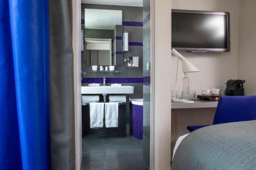 巴黎普拉帝酒店的酒店客房设有带水槽的浴室和电视。