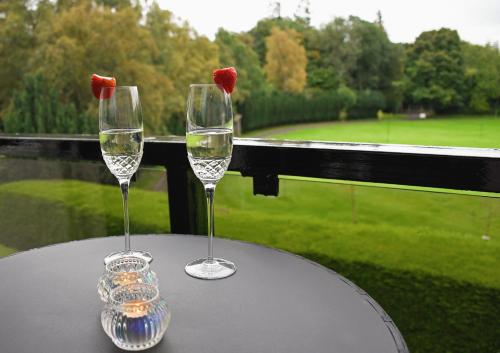 奥赫特拉德Gleneagles Luxury Apartments的桌上放两杯酒,享有高尔夫球场的景色
